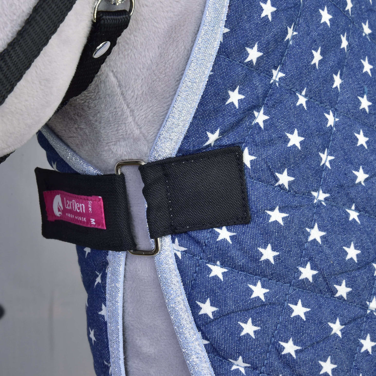 Close-up of the black chest strap with metal buckle and pink LarDen label on the navy Hobby Horse Stable Blanket Star