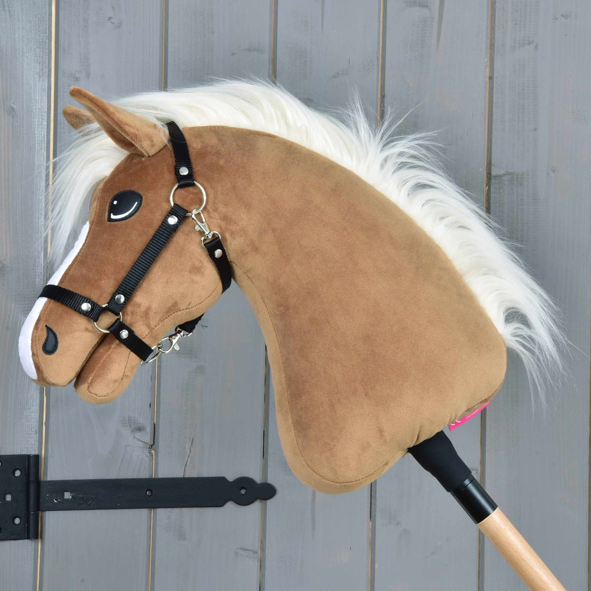 Hobby Horse Star in profile with the black halter, a caramel plush neck and a flowing white mane on a wooden stick