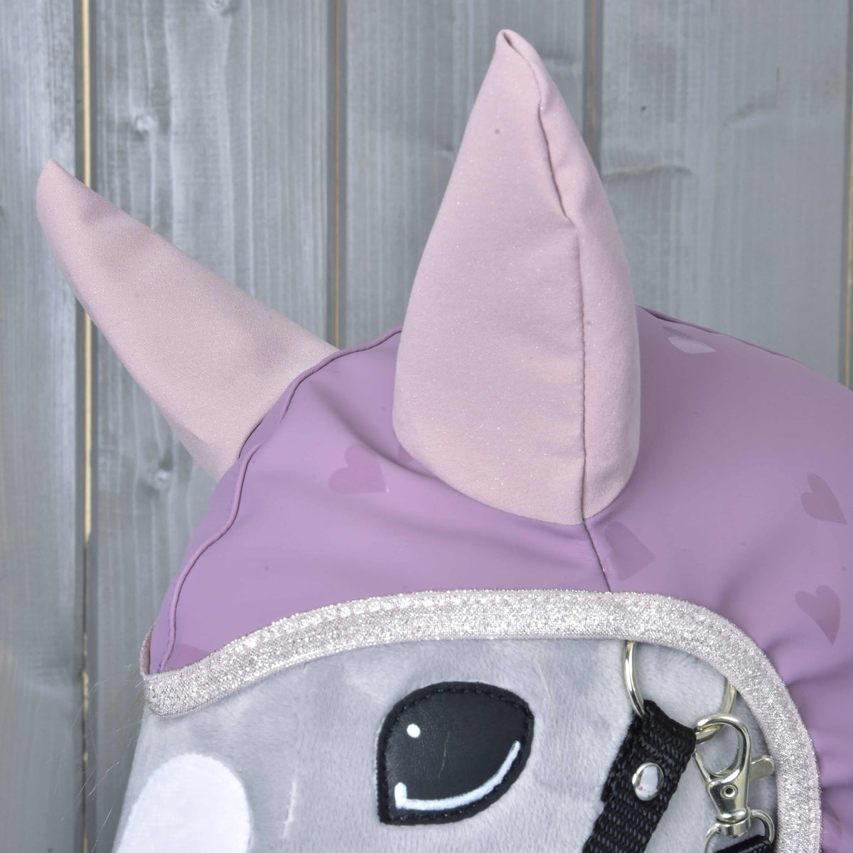 Close-up of the Raincoat Sweetheart hood on a grey Hobby Horse: shimmering pale pink ears and silver glitter trim