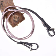 Hobby Horse Reins rubberized Dark Grey/Pink by LarDen, pale pink middle and dark grey buckle ends, looped over a branch