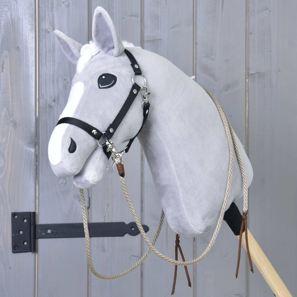 Grey Hobby Horse in a black halter with the beige split western reins clipped on and brown leather ends at the neck