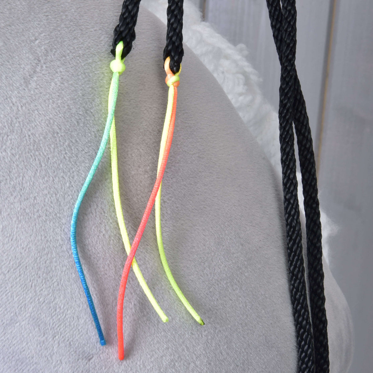 Close-up of the blue, yellow and orange neon cords knotted onto the black braided western reins
