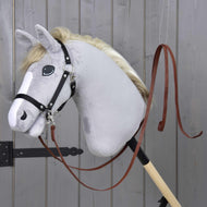 Light grey Hobby Horse with a black halter and the Split Western Reins Dark Brown clipped to it, by a grey wooden door