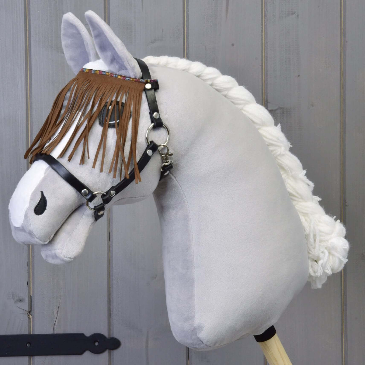 LarDen Halter black with brown fringes on a grey plush Hobby Horse, the suede-look fringes hanging over the eyes