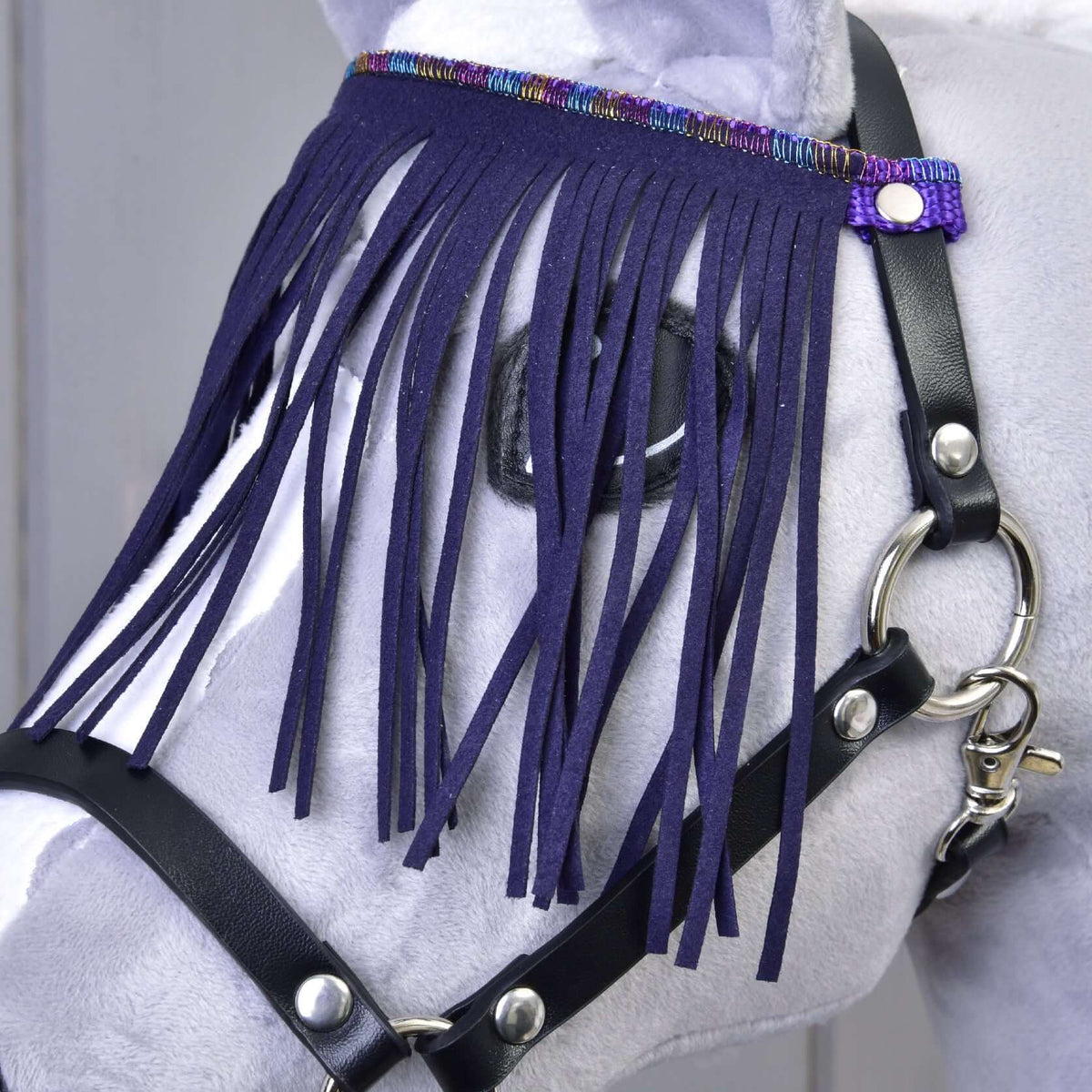 Närbild på de mörklila fransarna med skimrande vävd bård på grimman av svart konstläder för Hobby Horse